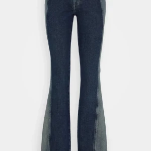 Blå bootcut jeans med tvåtonseffekt - Snygga blå bootcut jeans med cool tvåtonseffekt längs benen. Jeansen har klassisk femficksdesign och är tillverkade i jeansmaterial med stretch. Perfekta för dig som vill sticka ut lite extra med din denimstil.