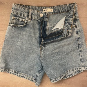 Högmidjade jeansshorts från g perfect jeans - Snygga högmidjade jeansshorts från g perfect jeans i klassisk ljusblå denim. Modellen har fem fickor, bälteshällor och stängs med dragkedja och knapp. Perfekta för sommardagar och ger en avslappnad vibe till din outfit.