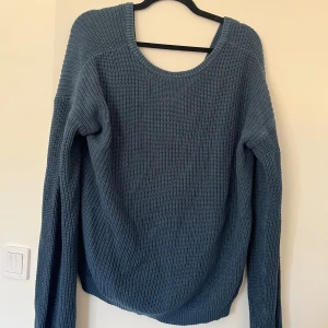Blå stickad tröja med v-ringning - Mysig blå stickad tröja med v-ringning på ryggen och lång ärm. 