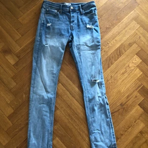 Slim fit jeans från Jack & Jones - Ljusblå jeans med slitningar från Jack & Jones. Riktigt feta nu till sommaren, ge prisförslag!
