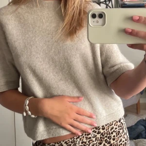 Stickad tröja - Supermjuk och stilren beige stickad tröja med korta ärmar och rund hals. Perfekt till både jeans och kjol, och den har en avslappnad passform som känns chill och enkel att styla.