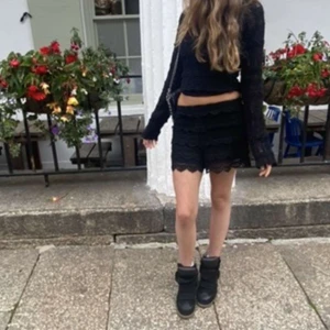 Svarta virkade shorts med spetsdetaljer - Snygga svarta shorts med virkad spets och vågig kant. De har elastisk midja och är fodrade för att inte vara genomskinliga. Perfekta till sommaren när du vill ha en chill men ändå uppklädd look. Passar till crop tops eller stickade tröjor.