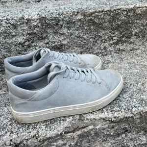 Ljusgrå mockasneakers stl 42 - Snygga ljusgrå sneakers i mocka från IEB!ER. Klassisk modell med rund tå, snörning och vit platt sula. Perfekta för dig som gillar stilrena och minimalistiska skor. Passar till det mesta och är riktigt bekväma.
