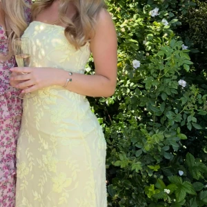 Ljusgul axelbandslös långklänning - Superfin ljusgul långklänning med axelbandslös design och broderade blommor över hela klänningen. Använt en gång men köpte från Plick då den ej var använd🌸🌸