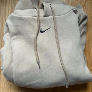 Beige Nike hoodie  - Snygg beige hoodie från Nike med klassisk svart swoosh-logga på bröstet. Tröjan är i bra skick och är använd några gånger. 7,5/10. Skriv gärna om du har frågor👍