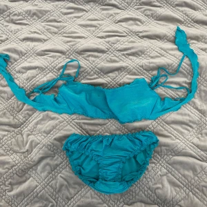 Turkos bikini med snörning - Det finns en liten fläck. Vi kan komma överens om priset. 😀😀Snygg turkos bikini med scrunch-detaljer och knytband både upptill och nedtill. Överdelen har smockad look och axelband som knyts i ryggen. Perfekt för stranden eller poolen!
