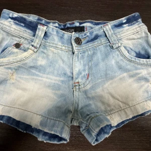 Jeansshorts  - Snygga ljusblå jeansshorts med slitna detaljer, jättefina nu till sommaren. Midjemåttet rakt över är 35 cm. Obs! Jag är på semester och kan därmed skicka tidigast 28/6