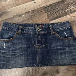 Mörk jeanskjol från Ravff - Snygg mörkblå jeanskjol från Ravff med slitna detaljer, klassiska fickor fram och bak samt synliga sömmar i kontrastfärg. Kjolen har knappstängning framtill. Perfekt för dig som gillar en cool och avslappnad stil. Storlek 36/S 😊 pris kan diskuteras 