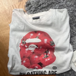 Vintage Vit BAPE t-shirt med röd print - Otroligt unik och sällsynt vintage bape tisha. Underbart skick och kvalité i top class🙉köpt i Japan på en vintage butik, inga skavanker eller skador. Pris kan såklart diskuteras vid snabba affärer 💴 .