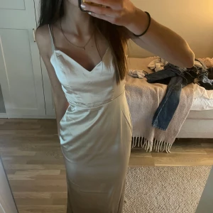 Balklänning - Champagnefärgad långklänning i satin. Ursprungspris är 1099. Köpte den på plick till balen för några veckor sedan men hittade en annan så bara använd av förra ägaren en gång, inga tecken på användning! Stor i storleken skulle jag säga. 