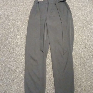 Svarta kostymbyxor Pull&Bear med bälte - Svarta kostymbyxor från Pull&Bear i storlek S med hög midja och tillhörande bälte. Byxorna har en rak och lite loose passform, elastisk midja bak och är perfekta för en clean och stilren look.