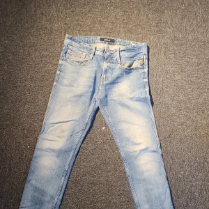 Ljusblå Replay jeans slim fit - Säljer ett par ljusblå jeans från Replay med snyggt slitna detaljer och klassisk femficksdesign. Jeansen har smal passform och är tillverkade i mjukt denimtyg med dragkedjegylf. Perfekta för en avslappnad och trendig look.