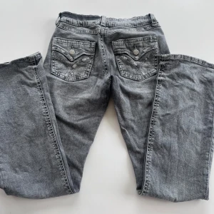 Grå jeans med broderade bakfickor - Low waist jeans med coola fickor. Lite slitnad på insida lår men syns knappt. Inte använd många gånger.