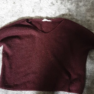 Vinröd stickad v-ringad tröja - Mysig vinröd stickad tröja med v-ringning och lite loose passform. Perfekt att slänga på sig när det är kallt ute. Långärmad och enkel att matcha med jeans eller kjol. Snyggt avslappnad stil som funkar året runt.