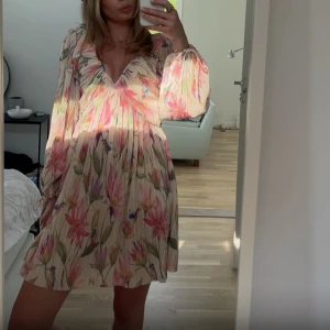 Klänning Hm - Superfin kortklänning med blommigt mönster.  Klänningen har v-ringning, volangdetalj vid halsen och långa, luftiga ärmar med knyt vid handlederna. Bara använt en gång💞