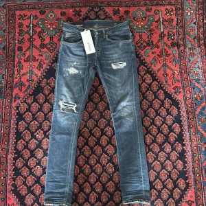 Blå skinny jeans från Dondup - Snygga blå skinny jeans från Dondup med slitna detaljer och trasiga partier på låren och knäet. Perfekta för dig som gillar en edgy streetstil.