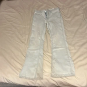 Ljusblå bootcut jeans från H&M - Säljer ett par ljusblå bootcut jeans från H&M med klassisk femficksdesign och normalhög midja. Jeansen har en snygg utsvängd passform nertill och är tillverkade i mjukt bomullstyg med lite stretch för extra komfort.