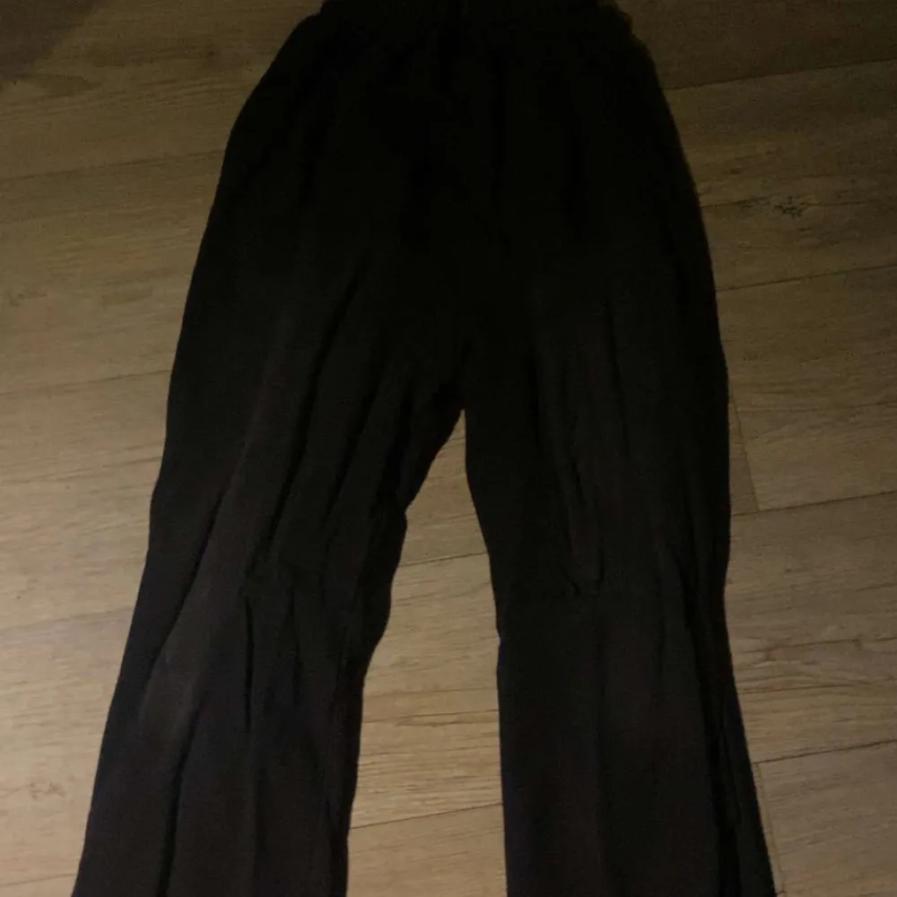 Coola svarta byxor med unika tryck i vitt, inklusive text och symboler. Byxorna har en avslappnad passform och elastisk midja för extra komfort. Perfekta för en avslappnad stil med en twist.. Farkut & Housut.