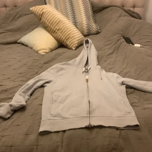 Grå hoodie från Morris - Säljer en stilren grå hoodie från Morris med dragkedja och broderad detalj på bröstet. Tröjan har långa ärmar och en bekväm passform. Perfekt för en avslappnad look. Den är i strl M men liten i storlek så passar ungefär 170! Skriv vid funderingar. Nytt skick!