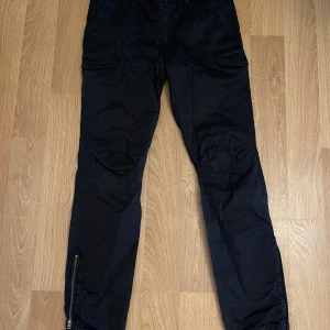 Svarta cargopants från Boomerang - Snygga svarta cargopants från boomerang med praktiska fickor och dragkedja vid bensluten. Perfekta för en avslappnad stil med en touch av funktionalitet.