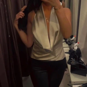 Beige halterneck topp - Snygg beige halterneck topp med djup urringning och öppen rygg. Toppen har en knytning i ryggen som ger en elegant touch. Perfekt för en kväll ute!