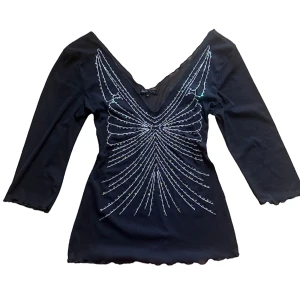 y2k vinrage Svart topp med paljettdetaljer - Snygg svart topp med v-ringning och glittriga paljettdetaljer i ett mönster framtill. Toppen har trekvartsärmar . Strl M men passar en S också. 