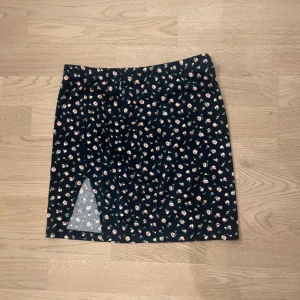 Blommig kortkjol - Snygg kortkjol med blommigt mönster. Kjolen har en liten slits framtill som ger en extra touch. Perfekt för sommarens alla tillfällen. Ska flytta snart så vill gärna bli av med allt så fort som möjligt (pris kan diskuteras)💕