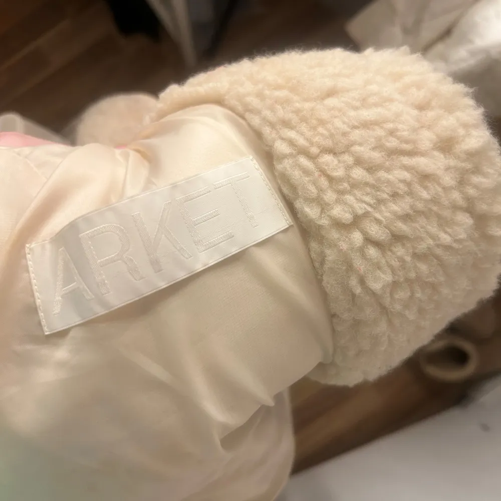 Mysig beige teddyjacka från Arket med dragkedja framtill. Perfekt för kyliga dagar med sin fluffiga och varma design. Jackan har en avslappnad passform och långa ärmar, vilket gör den både bekväm och stilren.. Takit.