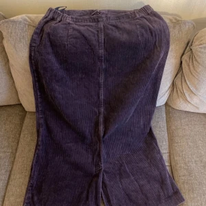 Lila manchesterkjol - Snygg lila manchesterkjol med dragkedja och knapp i på baksidan. Kjolen har en slits framtill som ger extra rörelsefrihet. Perfekt för en stilren look.