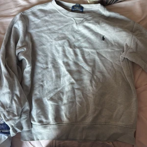 Grå sweatshirt från Ralph Lauren - Säljer en klassisk grå sweatshirt från Ralph Lauren med det ikoniska broderade logotypen på bröstet. Tröjan har rund hals och långa ärmar, perfekt för en avslappnad stil. Passar bra till både jeans och chinos. St 160