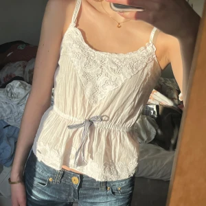 Vit spetsprydd linnetopp - Säljer en söt vit linnetopp med spetsdetaljer och broderier. 