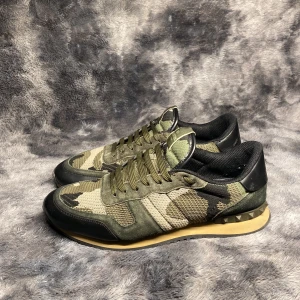 Valentino Rockrunners Dark Green Camo (2024 model) - Säljer dessa snygga valentino rockrunners för endast 2399kr. Skicket är bra, en synlig defekt på insidan av skon (7-10).  Storlek 43. Endast skorna medföljer. Om ni har några frågor om detta tveka inte att fråga! 