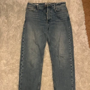 Blå jeansbyxor Loose/Chris - Säljer ett par blå jeansbyxor med loose fit. De har en klassisk femficksdesign och knappgylf. Perfekta för en avslappnad stil. Storlek 29/32
