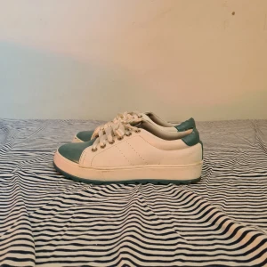 Vita och blåa sneakers från Bcp selection - Snygga vita sneakers med blåa/turkosa  detaljer från Bcp selection. Skorna har snörning av siden och en robust sula som ger bra grepp. Perfekta för en avslappnad stil. Storlek 38, men passar 36-38 också🩵