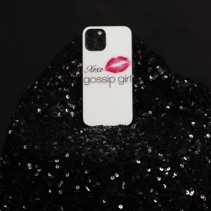 Mobilskal med Gossip Girl-design - Snyggt mobilskal med texten 'Xoxo gossip girl' och en röd läppstiftskyss. Skalet är vitt och passar perfekt för fans av serien. Perfekt för att ge din telefon en stilfull och personlig touch.
