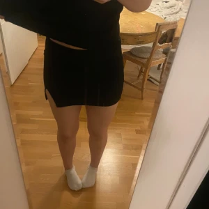 Svart kortkjol med slits - Snygg svart kortkjol med en liten slits på sidan. Perfekt för en stilren look. Kjolen har en tight passform men stretchig. lappen är kvar alltså ej använd. 