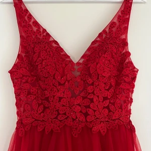 Röd balklänning / långklänning - Säljer min fina balklänning som bara har använts en gång. Klänningen har en fin v-ringning fram till i spets, med en öppen rygg. Den sitter väldigt smickrande på kroppen ❤️ Från märket Mascara.