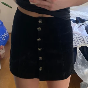 Svart manchesterkjol från H&M Divided - Snygg svart manchesterkjol från H&M Divided med knappar framtill. 100% bomull och storlek 36