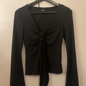 Svart långärmad knyt-topp från gina tricot - Snygg svart långärmad topp från gina tricot med knytning framtill. Perfekt för en stilren look. Toppen har en v-ringad design. superbra skick!💓