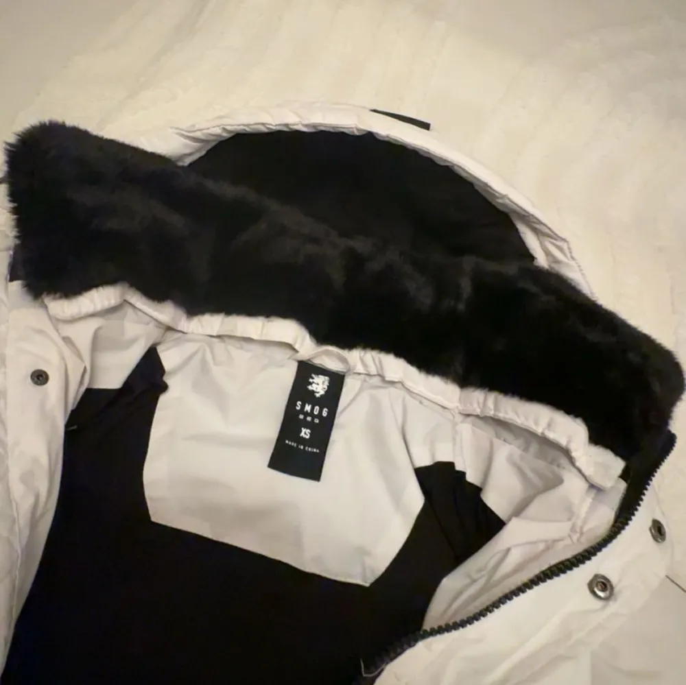 Säljer en snygg vit pufferjacka med huva och svarta detaljer. Jackan har dragkedja och knappar framtill samt praktiska fickor. Perfekt för kalla dagar!. Takit.