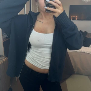 Svart stickad cardigan kofta - Säljer en svart stickad cardigan kofta med dragkedja. Den har långa ärmar och ribbade muddar. Perfekt för en avslappnad stil.