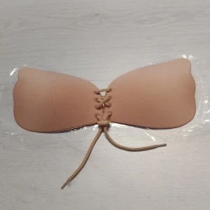 Beige självhäftande silikon bh A kupa - Självhäftande beige bikiniöverdel med snörning framtill för justerbar passform. Perfekt för att undvika solbrännelinjer. Enkel att använda och ger ett smidigt utseende under kläder.