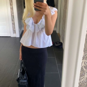 Vit blus med volangdetaljer - Säljer en söt vit blus med volangdetaljer och djup v-ringning. Blusen är ärmlös och har en luftig passform, perfekt för varma dagar. Den är tillverkad i ett lätt och bekvämt material.❤️