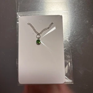 Silverarmband med grön pärla - Elegant silverarmband med en grön pärla som hänge. Perfekt för att lägga till en färgklick till din outfit. Kedjan är tunn och smidig, vilket gör den lätt att bära. (