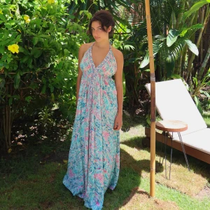 Lång ibiza klänning - Långklänning. Oanvänd. Storlek One size för att knyterna går att dra år efter behov runt midjan och bakom nacken. 70% silke och 30% viskos med guldfolie. Perfekt för sommaren