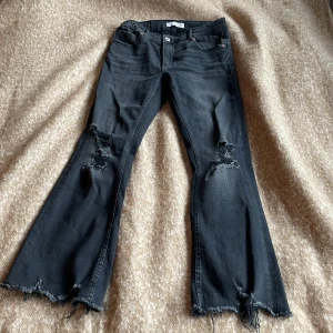 Svarta bootcut jeans från Zara - Snygga svarta bootcut jeans från Zara med slitna detaljer på knäna och fransiga benslut. Dom har legat kvar i garderoben och har använt dom kanske 2 gånger. 🖤