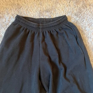 Svarta mjukisbyxor med text - Svarta mjukisbyxor med elastisk midja och texten 'CHEERLEADER' i vitt längs benet. Perfekta för en avslappnad stil.