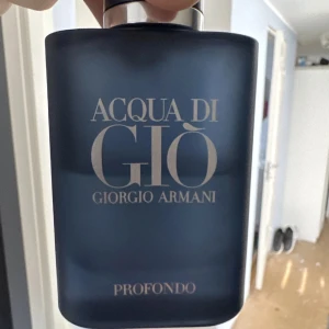 Acqua di Giò Profondo från Giorgio Armani - Säljer en flaska Acqua di Giò Profondo från Giorgio Armani. Flaskan är mörkblå med en elegant, matt finish och har en silverfärgad kork. Denna doft är känd för sina friska och marina toner, perfekt för den som älskar en fräsch och sofistikerad parfym.