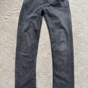 Grå jeansbyxor från Replay - Snygga svart/mörgråa jeansbyxor från Replay, modell Grover. De har en straight fit och är tillverkade i återvunnet material. Perfekta för en stilren look.