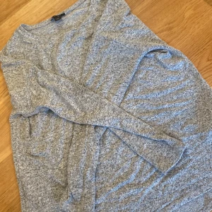 Grå stickad tröja - Säljer en mysig grå stickad tröja med långärmad design. Perfekt för kyligare dagar och enkel att matcha med olika outfits. Tröjan har en klassisk rund hals och är tillverkad i ett mjukt material.